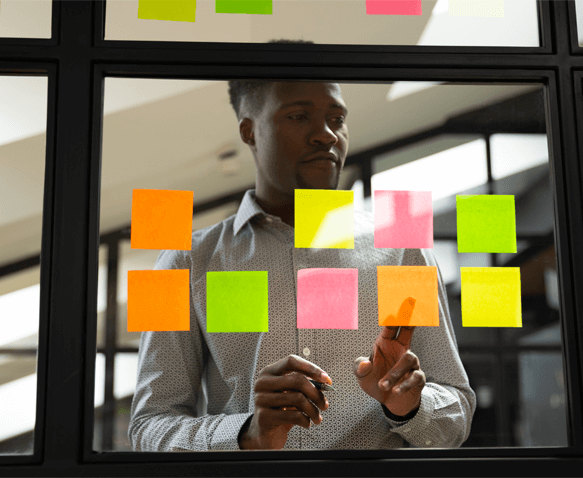 A productive employee busy sticking sticky notes onto a glass wall.